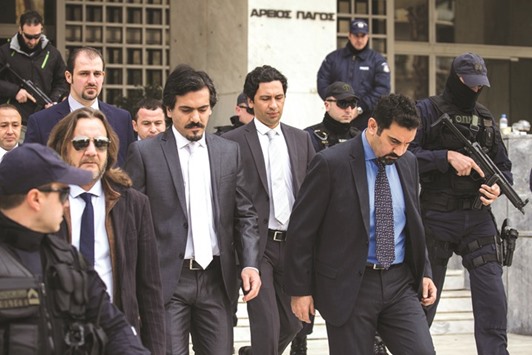 Some of the eight Turkish soldiers are escorted by police officers as they leave the Supreme Court in Athens.