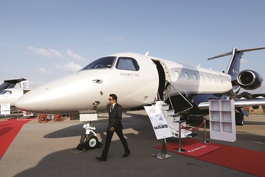 An attendee walks past an Embraer Legacy 500 jet on display at the Singapore Airshow held at the Changi Exhibition Centre on February 16, 2016. Brazilian planemaker Embraer, the worldu2019s biggest maker of regional jets, said itu2019s optimistic that a US government led by Donald Trump will still grant it the clearances needed to sell aircraft to Iran.