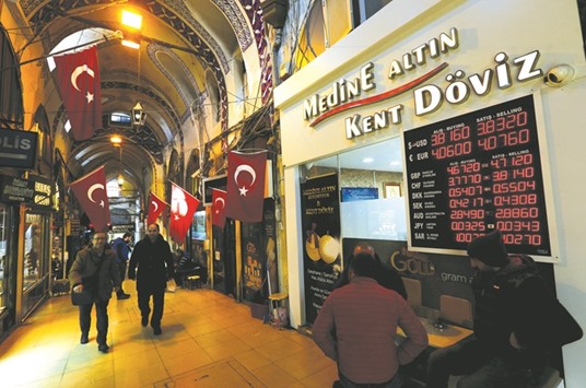 Merchants chat in front of a currency exchange office at the historical Grand Bazaar, known as the Covered Bazaar, in Istanbul on January 12. With the lira trading at record lows against the dollar, the central bank rolled out a series of unorthodox measures in recent weeks, including using swaps to smooth volatility.