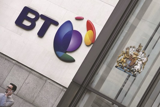 A man speaks on a mobile phone underneath a BT logo in London. Shares in the British telecom firm plunged 20% yesterday after the company warned that its profits would take a much larger hit than expected from accounting irregularities in Italy.