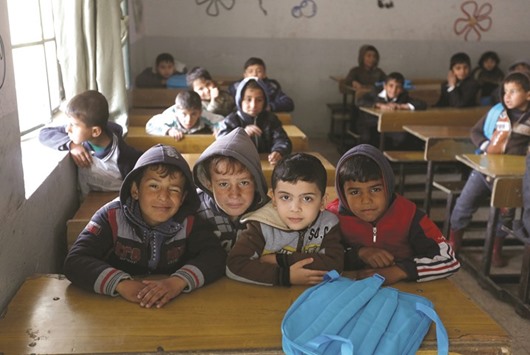 School children react to a camera as they attend a class after registering in school in Mosul, Iraq.