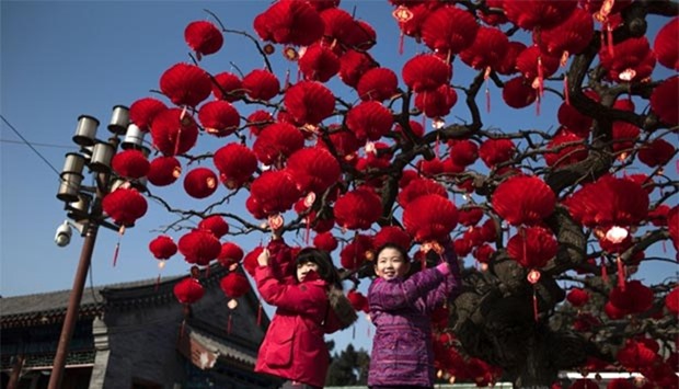 Chinese children pose for a photograph beside a lantern tree display ahead of the Lunar New Year in Beijing on Wednesday.