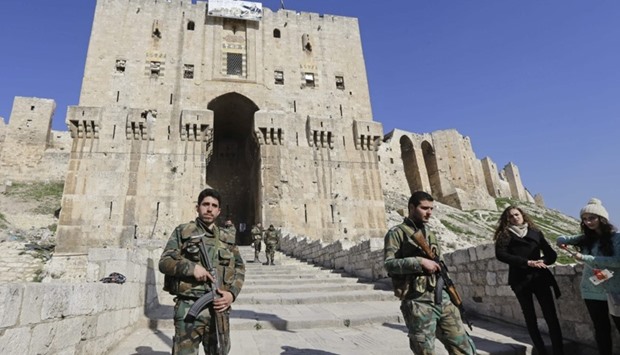 Syrian soldiers stand guard as Syrians visit the Aleppo Citadel on January 22, 2017, a month after Syrian government forces retook the northern city from rebel fighters.