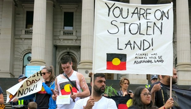 Aboriginal protesters hold signs as they demonstrate outside the Victorian State Parliament