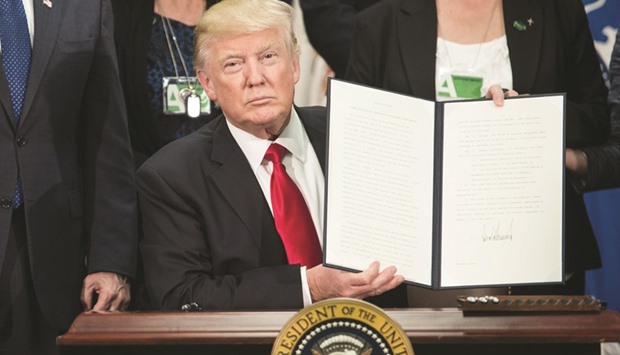 US President Donald Trump poses with an executive order that he signed on Wednesday to start the Mexico border wall project at the Department of Homeland Security facility in Washington, DC.
