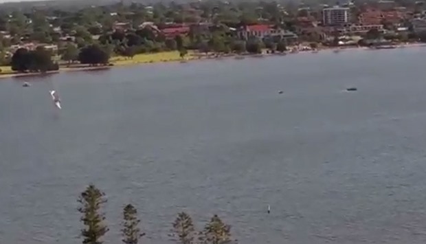 An image grab from the video that shows the seaplane (L) about to fall into the river.