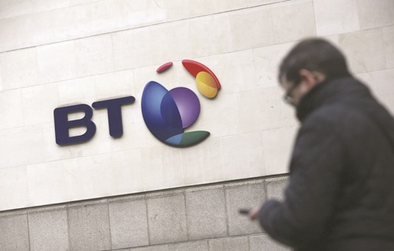 A man checks his mobile phone as he passes a sign displayed outside the BT building in London. BT stunned the market on Tuesday when it said a complex accounting scandal in Italy had blown a u00a3530mn ($665mn) hole in its accounts, while demand from the British government had slowed, forcing it to cut profit targets for the next two years.