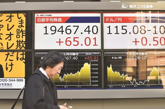 A pedestrian walks past an electronic quotation board flashing stock prices of the Tokyo Stock Exchange. Japanese shares rose 0.3% to 19,467.40 as the dollar held Thursdayu2019s rise against the yen.