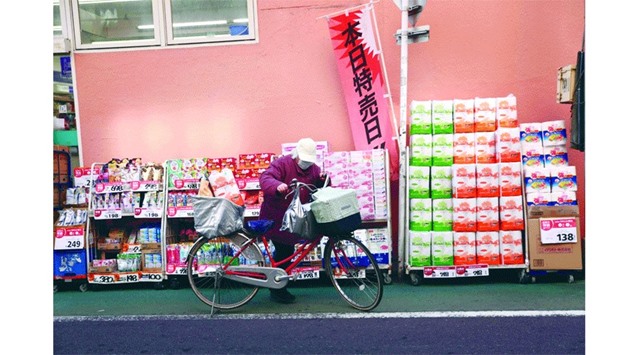 A shopper prepares to ride his bicycle loaded with groceries at a supermarket in Tokyo. Japan yesterday logged its first annual consumer price decline in four years, underscoring the challenges facing Tokyou2019s fight to rid the worldu2019s number three economy of deflation.