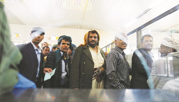 Public sector employees wait to receive their salaries at a post office in Sanaa, Yemen.