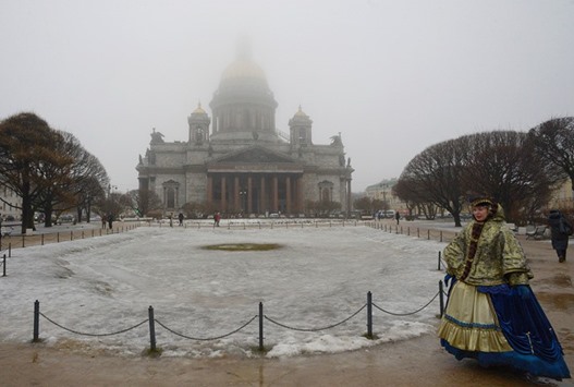 A woman in period costume walks past St Isaacu2019s cathedral in Saint Petersburg.