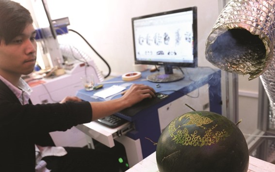 A technician uses a computer to create a laser-carving on a watermelon at Nguyen Van Minhu2019s workshop in Hanoi.