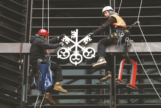 Workmen, suspend from wires, take down a UBS Group logo from their old offices at Broadgate circle in London. UBS, among the few European banks still facing a US probe into sales of mortgage securities, set aside 162mn francs during the quarter to cover litigation expenses, less than the 544mn francs analysts had expected.