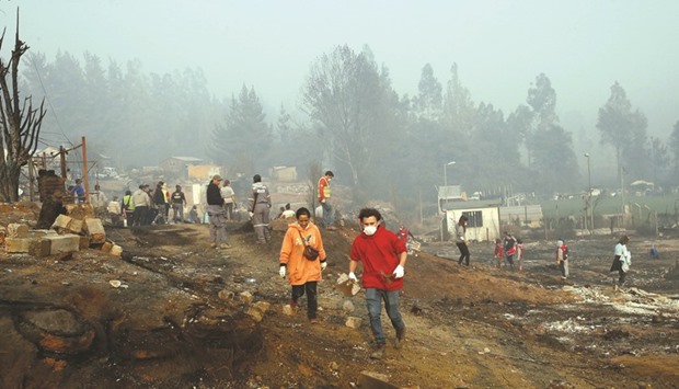 People walk among the remains of burnt houses after a wildfire in Santa Olga, in Chileu2019s central-south regions, on Saturday.