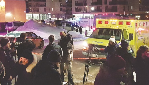 Media personnel wait at the scene of a fatal shooting at the Quebec Islamic Cultural Centre in Quebec City.