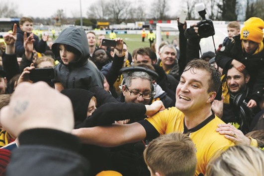Sutton Unitedu2019s Jamie Collins celebrates with supporters on the pitch after their win in the English FA Cup fourth round match against Leeds United in London on Sunday. (AFP)
