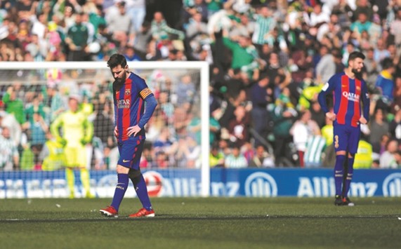 Barcelonau2019s Lionel Messi and Gerard Pique react to a Real Betis goal during their La Liga match in Seville, Spain, on Sunday. Barca slipped further behind Real Madrid at the top of the standings in a controversial 1-1 draw against Betis. (Reuters)