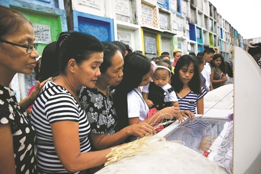 Loved ones and mourners pay their last respects to the lifeless bodies of Maximo Pepito, 49, and his brother Marlon Pepito, 42, victims of a summary execution by unknown assailants related to the drug war, during their funeral at the Navotas cemetery, north of Metro Manila, yesterday.