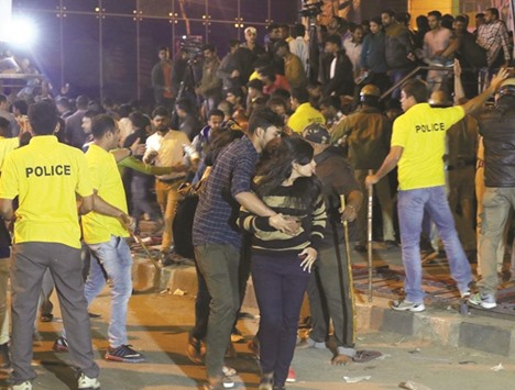 In this photograph taken on January 1, a man is seen helping a woman leave as police try to manage crowds during New Yearu2019s eve celebrations in Bengaluru.