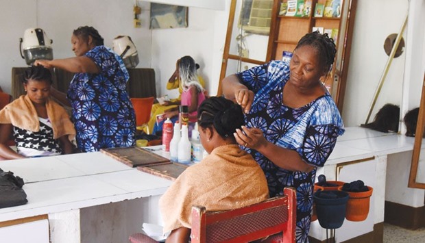 A woman who gets her hair done reads a book from a little library at a hairdresseru2019s in Abidjan.