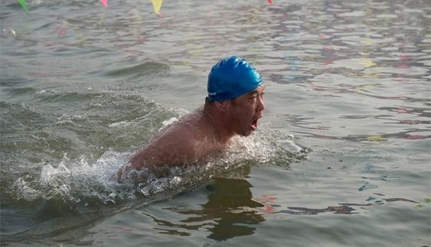 A participant swims in a pool cut from the frozen riverbank as part of a winter swimming competition during the 33rd Harbin Ice and Snow festival in Harbin on Thursday.