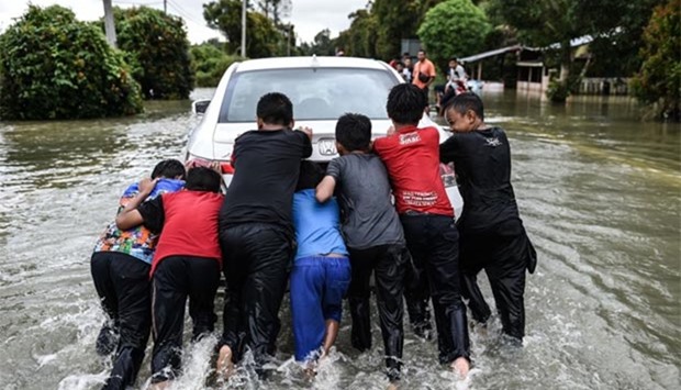 Children push a stalled car through floodwaters in Jal Besar, Malaysia's northeastern town of Tumpat on Thursday.