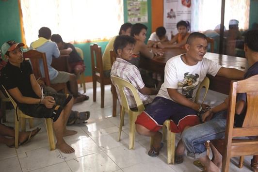 A group of captured inmates sit at a villager centre in Kabacan on the southern island of Mindanao yesterday.