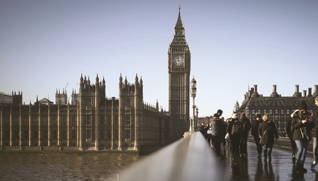 Tourists cross Westminster Bridge beside the Houses of Parliament in London. Britainu2019s economy probably grew 0.5% in the final three months of 2016, barely slowing from the robust pace seen in the three months just after the Brexit vote, Markit says.