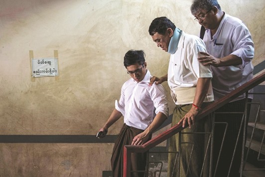 Than Htut Aung (centre), the detained CEO of the Eleven Media Group, is assisted down the stairs of the court house in Yangon yesterday. Two Myanmar media executives were granted bail in a high-profile defamation case that has become a lightning rod for fears over teetering press freedoms under the new democratic government.