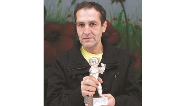 This file photo taken on January 24, 2014 shows Nazif Mujic, who won a Silver Bear for best actor at the Berlinale Film Festival in 2013, posing with his trophy outside a refugee centre in the western Berlin district of Gatow. Mujic has sold the award in order to provide for his family.