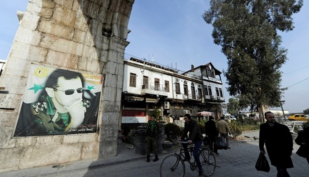 People walk past a picture of Syria's President Bashar al-Assad at Bab Sharqi entrance, near the Jobar district of Damascus, Syria. Reuters