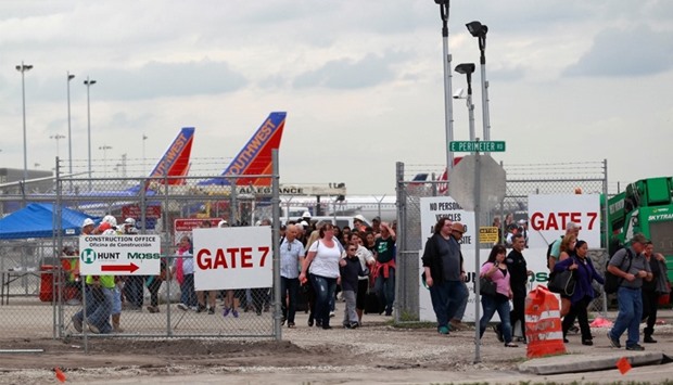 People exit the airport perimeter following a shooting incident at Fort Lauderdale-Hollywood International Airport