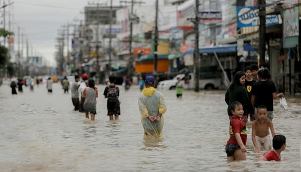 People walk in a flooded street at Muang district in Nakhon Si Thammarat Province