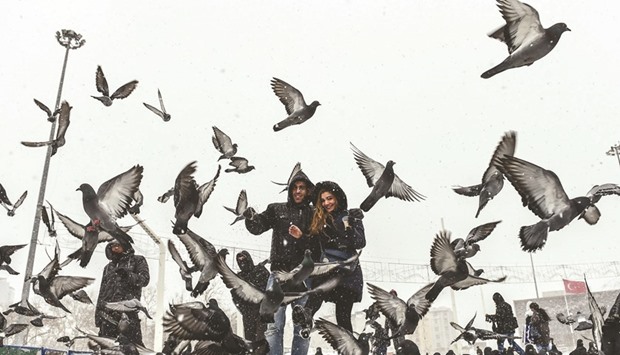 People walk near pigeons on Istanbulu2019s Taksim Square