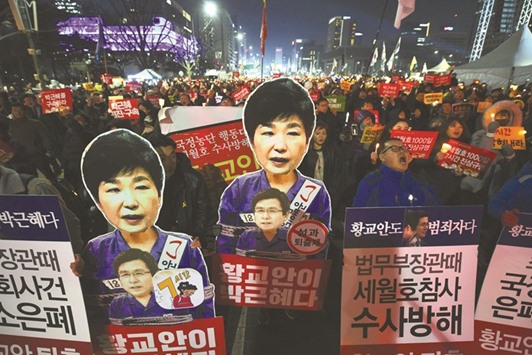 Protesters carry portraits of South Koreau2019s President Park Geun-Hye during a protest in Seoul yesterday demanding the impeached leader resign immediately.