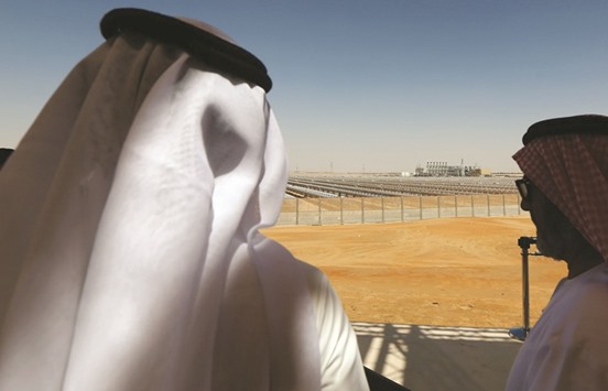 Emarati men stand on a balcony overlooking the Shams 1, Concentrated Solar power plant, in Al-Gharibiyah district on the outskirts of Abu Dhabi (file). In 2016, countries from Chile to the UAE broke records with deals to generate electricity from sunshine for less than 3 cents a kilowatt-hour, half the average global cost of coal power.