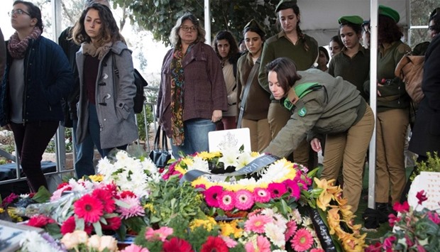 Friends and relatives of Israeli soldier mourn in front of his grave during his funeral