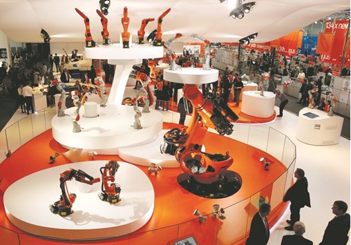 Visitors watch different sized industrial robots by Kuka at the Hanover Messe in Germany.