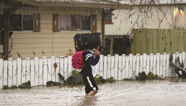 Cesar Belvasco walks through a flooded road while carrying his belongings after his home was flooded by the overflowing Petaluma River during a winter storm in Petaluma, California.