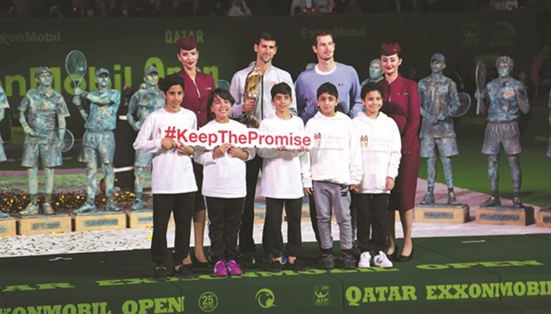Andy Murray and Novak Djokovic pose with children holding EAC signboard at the award ceremony of the championship.