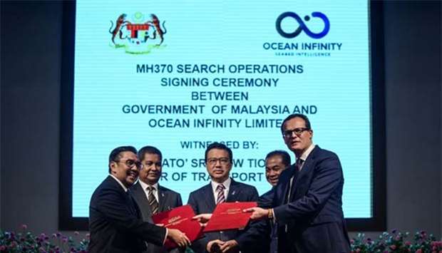 Director General of Malaysia's Civil Aviation Department Azharuddin Abdul Rahman (left) exchanges documents with CEO of Ocean Infinity Limited Oliver Plunkett (right) as Malaysia's Transport Minister Liow Tiong Lai (centre) looks on during a signing ceremony to resume the search for missing Malaysia Airlines flight MH370 in Putrajaya on Wednesday.