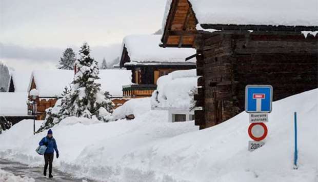 A pedestrian walks in the small resort of Zinal, Swiss Alps, after the access road cut by heavy snowfall reopened on Tuesday.
