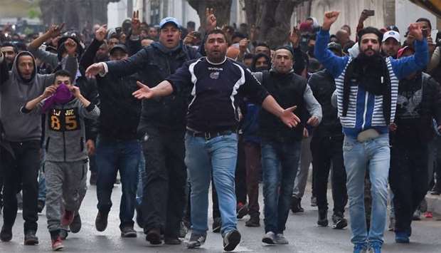 Tunisian protesters gesture towards security forces during clashes in the town of Tebourba