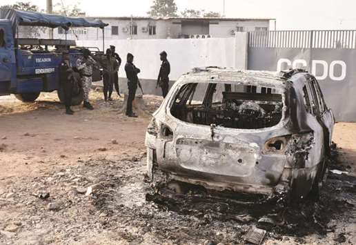 Soldier stand besides a burned car in front of the Co-ordination Center for Operational Decisions in Bouake yesterday.