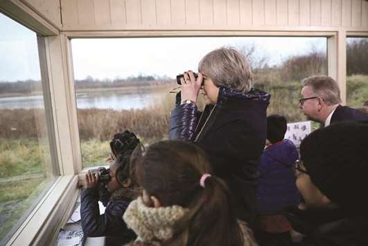 Prime Minister Theresa May watches birds from inside a bird hide as she stands with school children at the London Wetland Centre in west London yesterday.