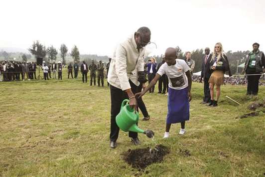 President of African Wildlife Foundation (AWF) Kaddu Sebunya and a student from a primary school built by tourism revenues, water a plant during an event of handing over a land in Musanze district, Northern Province. The African Wildlife Foundation has donated 27.8 hectares of land to Rwandau2019s national park in a bid to help the country expand habitat for the endangered mountain gorillas and other wildlife.