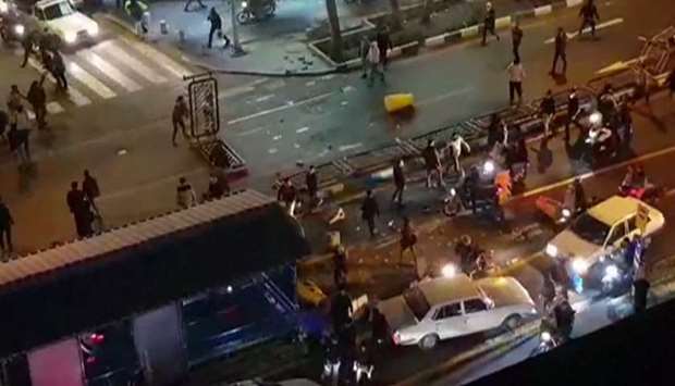 An image grab taken from a handout video released by Iran's Mehr News agency reportedly shows a group of men pushing traffic barriers in a street in Tehran on December 30, 2017
