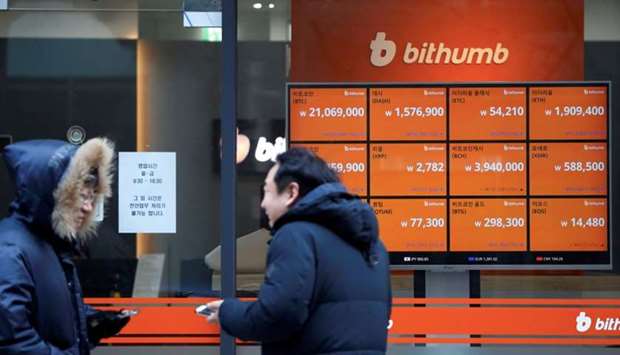 Men talk in front of an electric board showing exchange rates of various cryptocurrencies at Bithumb cryptocurrencies exchange in Seoul, South Korea.