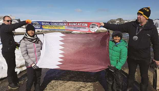 PRIDE: The siblings proudly display the Qatari flag after becoming the youngest runners to complete a marathon in Antarctica.