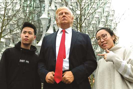 Pedestrians pose by a Madame Tussauds wax figure of US President Donald Trump outside the new US embassy in Embassy Gardens in southwest London yesterday.
